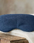 Linen & Wisewool™ sleep mask in blue, resting on a cream wool blanket