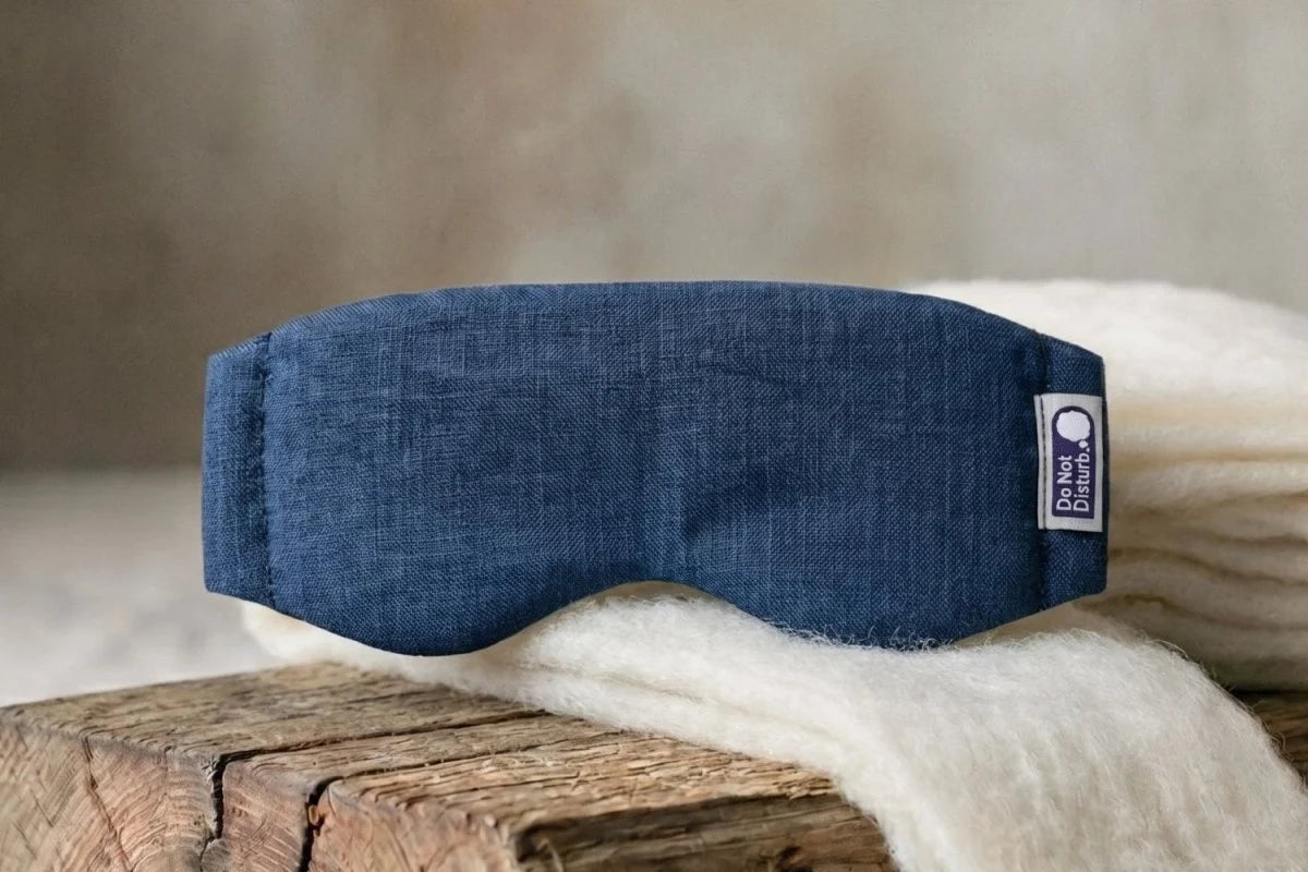 Linen & Wisewool™ sleep mask in blue, resting on a cream wool blanket
