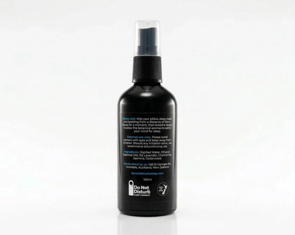 A black spray bottle with a clear cap and black spray nozzle, shown from the back on a white background. The back of the bottle features white text and a small white logo near the bottom.